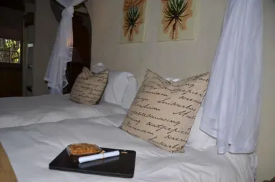 a tray of food on a bed with a book at Moholoholo Forest Camp in Hoedspruit