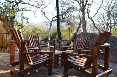 three wooden chairs and a table and a table and chairs at Moholoholo Forest Camp in Hoedspruit