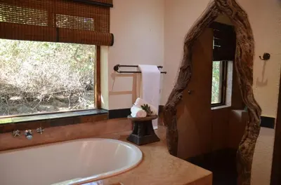 a bathroom with a large tub and a window at Moholoholo Forest Camp in Hoedspruit