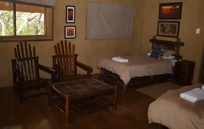a room with two beds and two chairs and a window at Moholoholo Mountain View in Hoedspruit