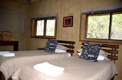 two beds in a room with two windows at Moholoholo Mountain View in Hoedspruit