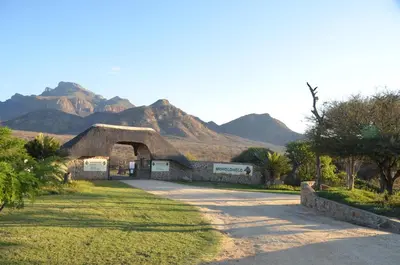 a building with a roof with mountains in the background at Moholoholo Mountain View in Hoedspruit