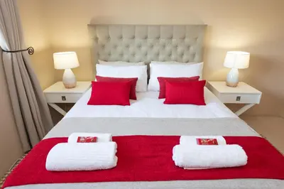 a bedroom with a large white bed with red pillows at Route 40 in Hoedspruit