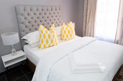 a bedroom with a white bed with yellow pillows at 3 Lux Suites in Middelburg