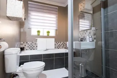 a bathroom with a toilet and a sink and a shower at 3 Lux Suites in Middelburg