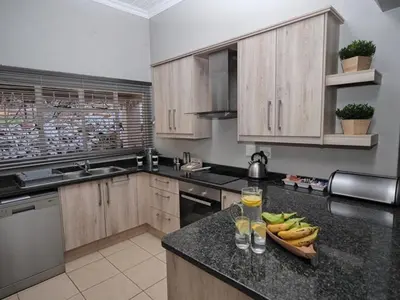 a kitchen with wooden cabinets and bananas on a counter at Poinsettia family Cottage in Hazyview