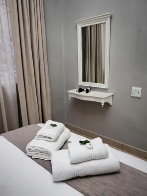 a bathroom with towels on a bed with a mirror at Poinsettia family Cottage in Hazyview