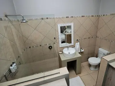 a bathroom with a shower and a sink and a toilet at Poinsettia family Cottage in Hazyview