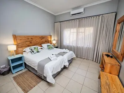 a bedroom with a large bed and a window at Poinsettia family Cottage in Hazyview