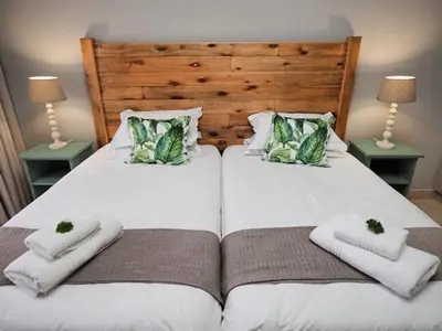 a bedroom with two beds with towels and two lamps at Poinsettia family Cottage in Hazyview