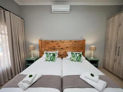 a bedroom with a large white bed with two pillows at Poinsettia family Cottage in Hazyview