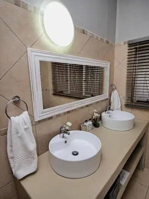a bathroom with two sinks and a mirror at Poinsettia family Cottage in Hazyview