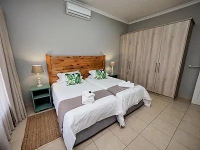 a bedroom with a large bed with a wooden headboard at Poinsettia family Cottage in Hazyview
