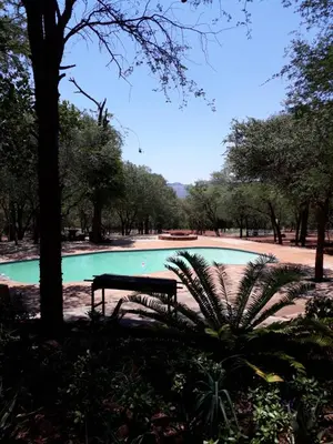 a park bench in front of a swimming pool at ThabaNkwe Bushveld Inn in Thabazimbi