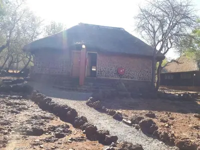 a brick house with a red door in a yard at ThabaNkwe Bushveld Inn in Thabazimbi