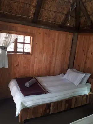 a bed in a room with a wooden wall at ThabaNkwe Bushveld Inn in Thabazimbi