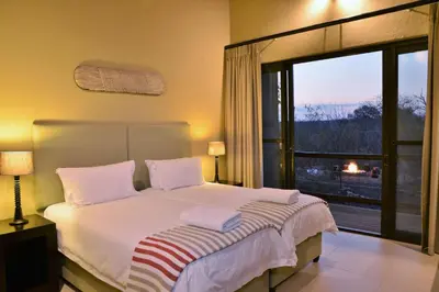 a bedroom with a bed and a large window at Mjejane Bush Camp by Dream Resorts in Hectorspruit