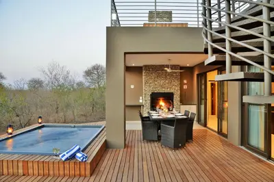 an outdoor deck with a swimming pool and a fireplace at Mjejane Bush Camp by Dream Resorts in Hectorspruit
