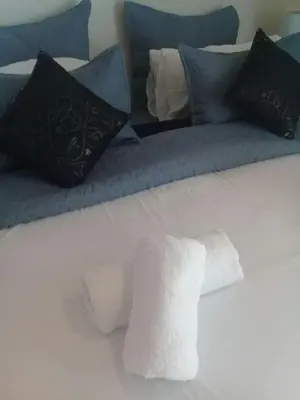 a bed with blue and black pillows on it at Shalamanzi Lodge in Hartbeespoort