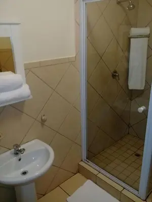 a bathroom with a shower and a sink at Shalamanzi Lodge in Hartbeespoort