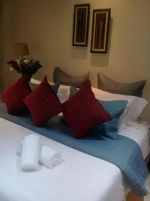 a bed with red and blue pillows on it at Shalamanzi Lodge in Hartbeespoort