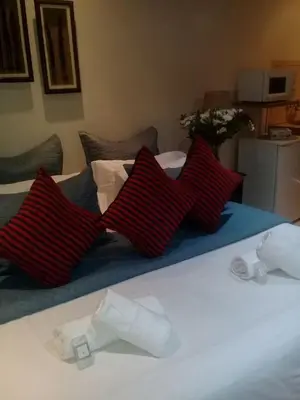 a bed with three red pillows on it at Shalamanzi Lodge in Hartbeespoort