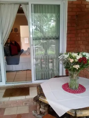 a vase of flowers on a table in front of a door at Shalamanzi Lodge in Hartbeespoort