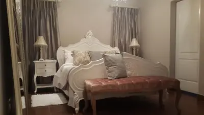 a bedroom with a white bed with a bench and a chair at Lavender House in White River