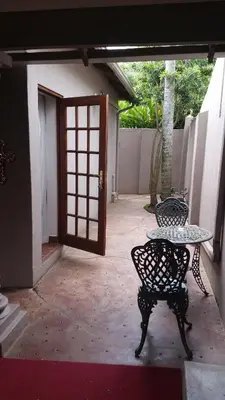 a patio with two chairs and a table and a door at Lavender House in White River