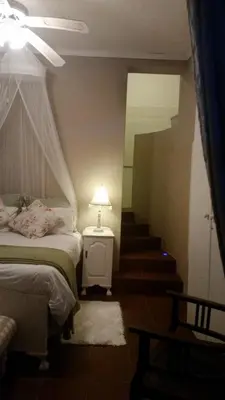 a bedroom with a bed and a staircase with a lamp at Lavender House in White River