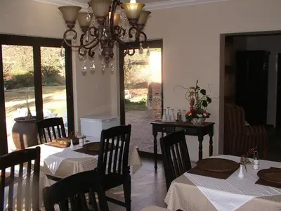 a dining room with tables and chairs and a chandelier at Villa Xanelle Boutique Guest House in Centurion