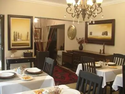 a dining room with white tables and chairs and a chandelier at Villa Xanelle Boutique Guest House in Centurion