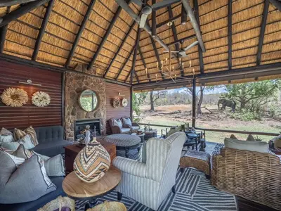 a living room with furniture and an elephant in the distance at Ndlovu Safari Lodge in Welgevonden Game Reserve