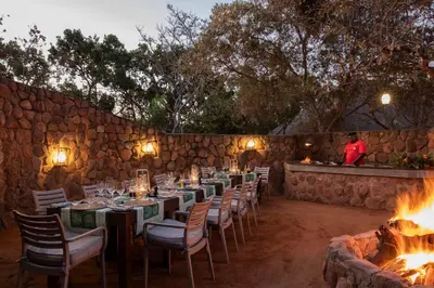 a dining room with tables and chairs and a fire place at Ndlovu Safari Lodge in Welgevonden Game Reserve