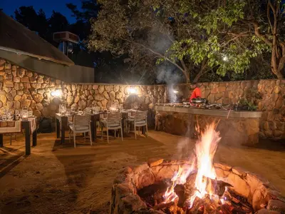 a fire pit at a restaurant with tables and chairs at Ndlovu Safari Lodge in Welgevonden Game Reserve