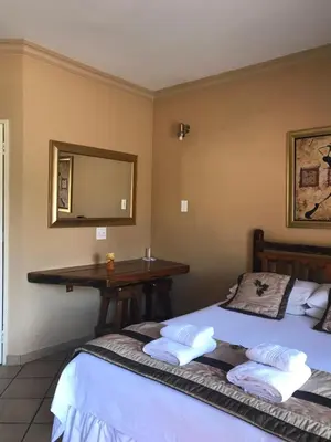 a bedroom with two beds and a desk with a mirror at Platinum Lodge Polokwane in Polokwane
