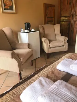 a living room with two chairs and a table at Platinum Lodge Polokwane in Polokwane