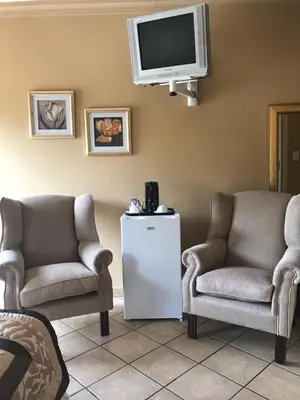 a living room with two chairs and a tv at Platinum Lodge Polokwane in Polokwane