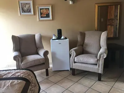 two chairs and a refrigerator in a room at Platinum Lodge Polokwane in Polokwane