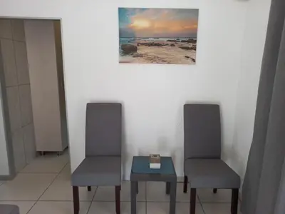 two chairs and a table with a clock on it at Tropical Paradise Guest House in Nelspruit