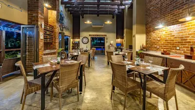 a restaurant with tables and chairs and a brick wall at Nkomazi Kruger Lodge & Spa in Malelane