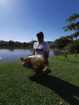 a man holding a large fish in front of a lake at Nkomazi Kruger Lodge & Spa in Malelane