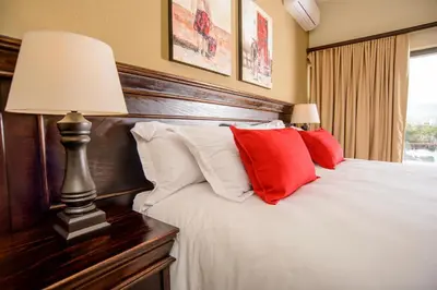 a bedroom with a bed with red and white pillows at Nkomazi Kruger Lodge & Spa in Malelane