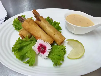 a white plate with some food on it with a bowl of dipping sauce at Nkomazi Kruger Lodge & Spa in Malelane