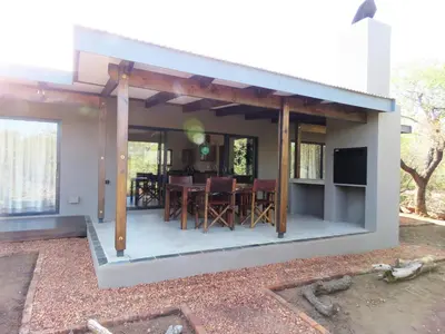 a house with a screened in porch with a dining room at Wild Dog Guest Lodge in Hoedspruit