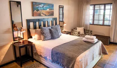 a bedroom with a large bed and a chair at Four Seasons Guesthouses in Lephalale