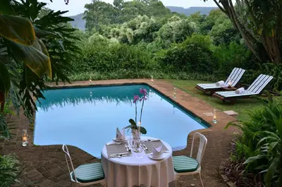 a table and chairs next to a swimming pool at Highgrove House Country Hotel, Restaurant, Farm & Spa in Hazyview