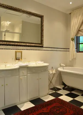a bathroom with two sinks and a tub and a mirror at Highgrove House Country Hotel, Restaurant, Farm & Spa in Hazyview