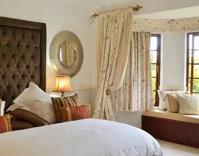 a bedroom with a bed and a mirror and a window at Highgrove House Country Hotel, Restaurant, Farm & Spa in Hazyview