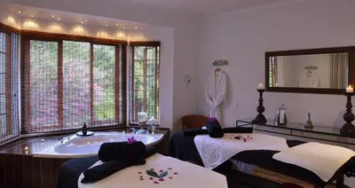 a spa room with a tub and two beds at Highgrove House Country Hotel, Restaurant, Farm & Spa in Hazyview